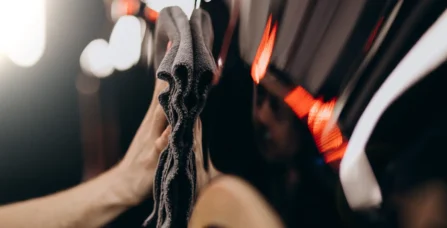 Процес професійного дейтейлінгу автомобіля: майстер протирає кузов мікрофіброю для досягнення ідеального блиску.